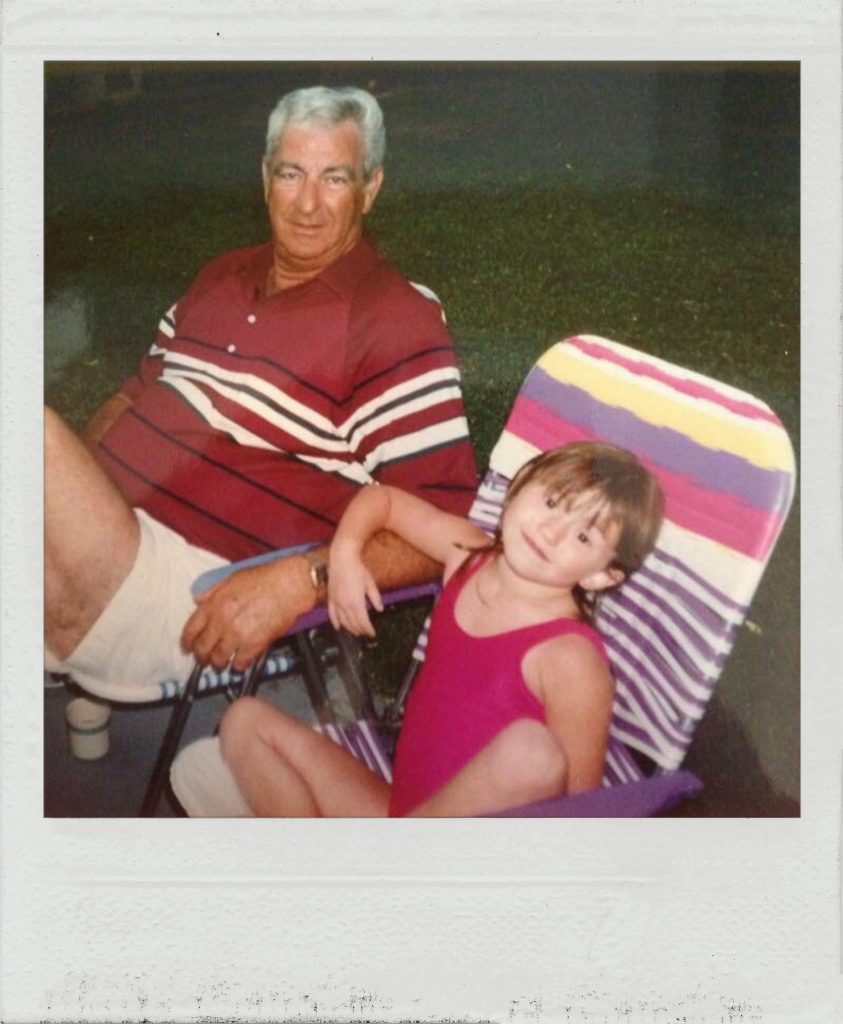 Grandfather and granddaughter in lounge chairs on lawn